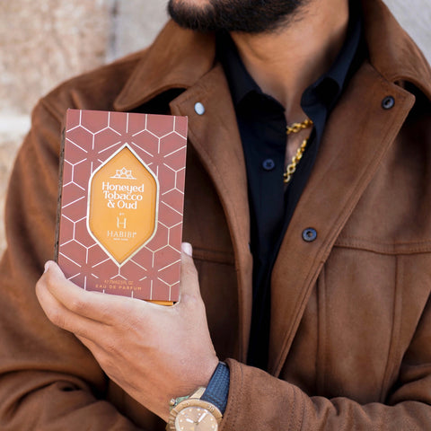 Honeyed tobacco and oud box held in hand with a man in a tan leather jacket